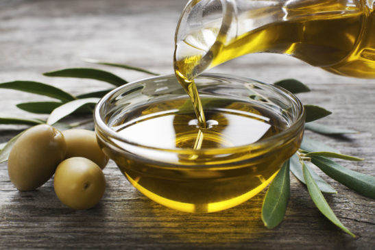 Olivenöl, das langsam von Karaffe in Schälchen gegossen wird