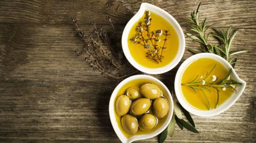 Olivenöl mit frischen Oliven in schönen Schälchen auf Tisch